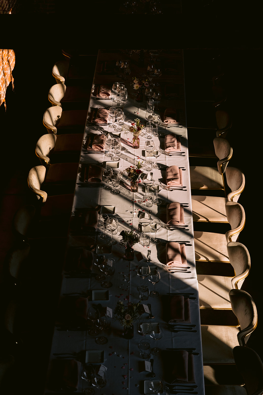 Wedding dinner table with glassware and floral details in dramatic light at Kasteel Rozelaar in Lochristi